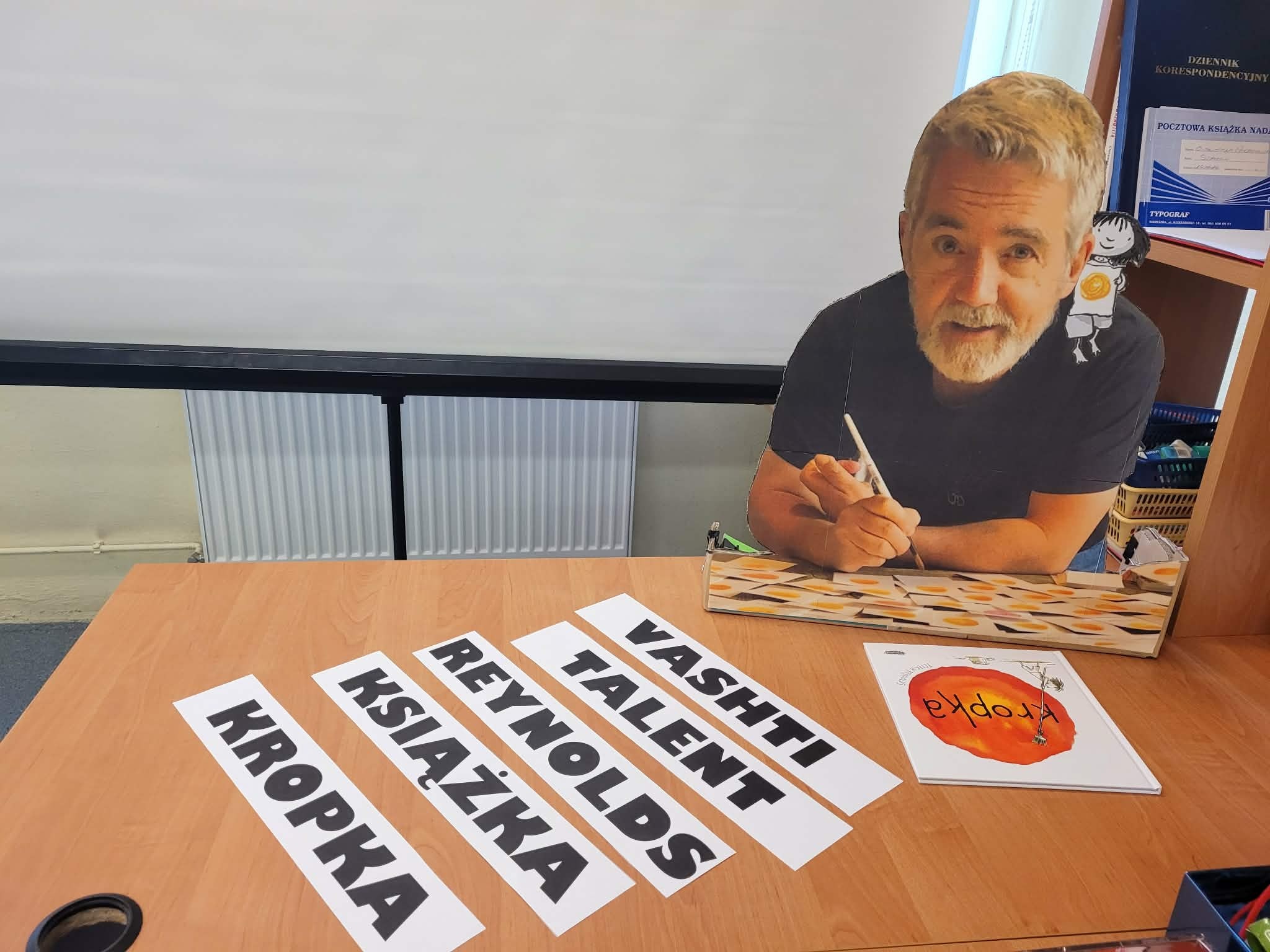 kartonowa postać Petera Reynoldsa siedzącego przy biurku